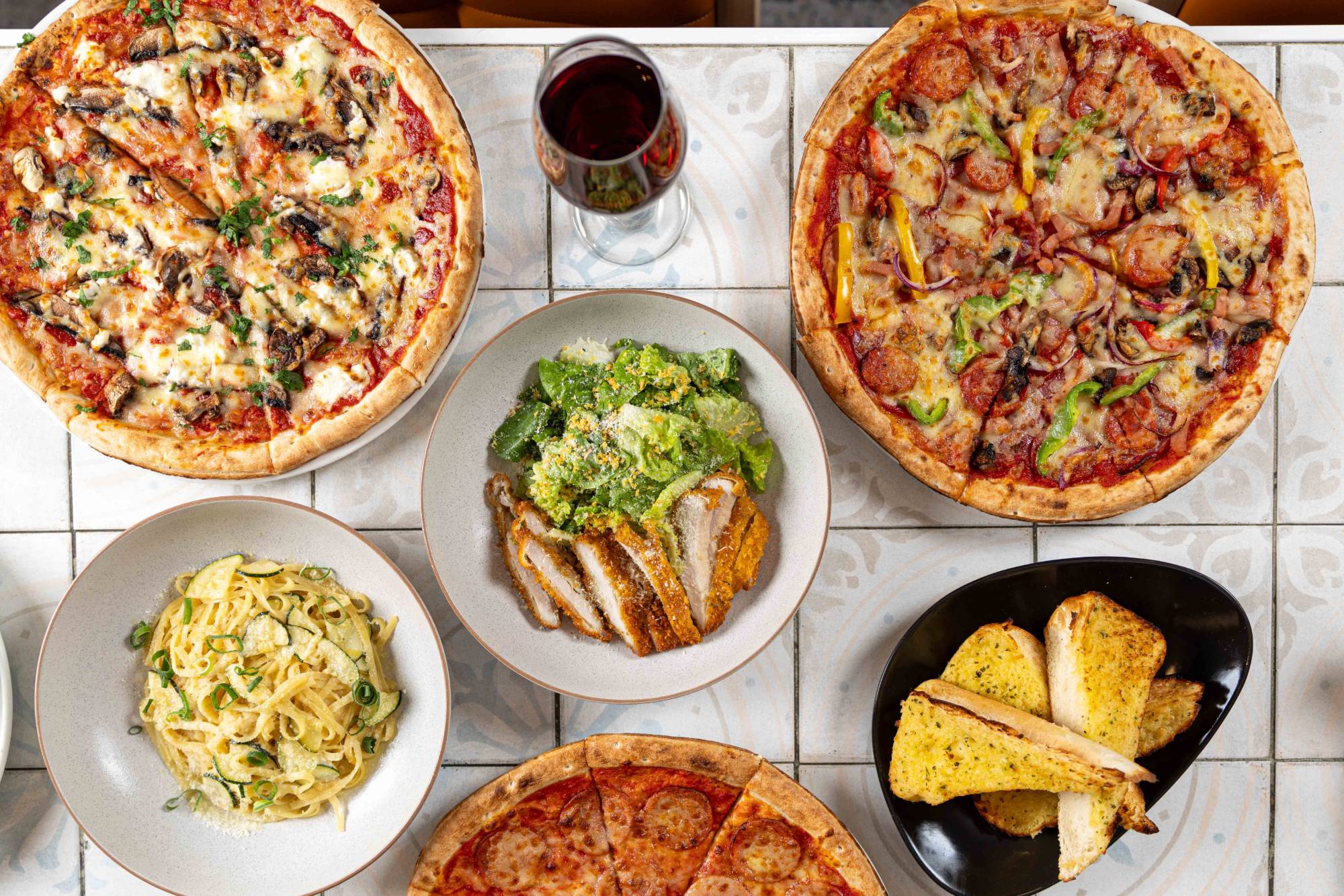 A spread of wood-fired pizzas, pasta, chicken schnitzel caesar and garlic bread at The Jack & Cleaver