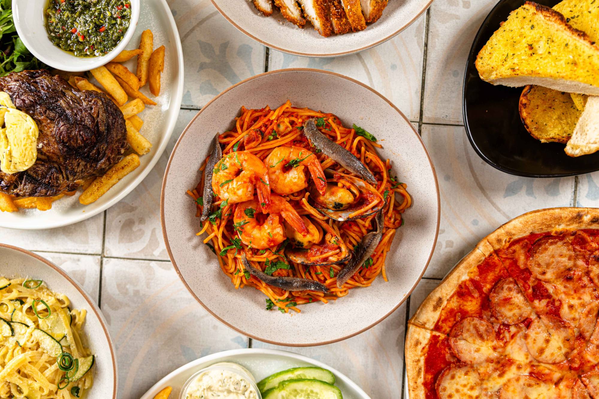 A spread of char-grilled steak, seafood pasta, wood-fired pizza and sides at The Fairway